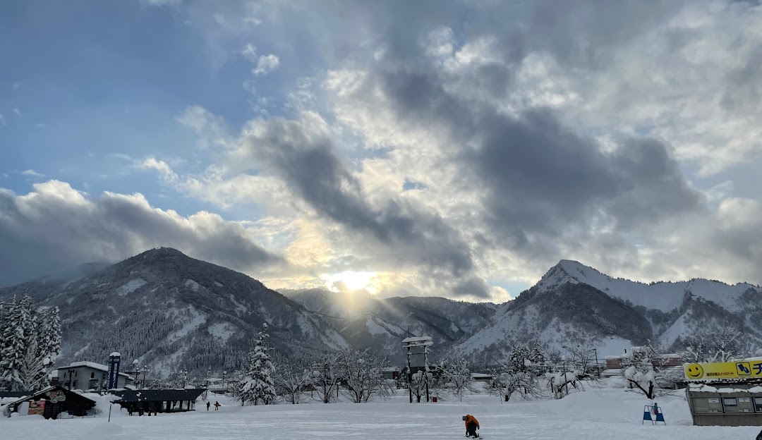 A beautiful winter scenery at Yuzawa Nakazato, Japan featuring a ski resort nestled amidst snow-covered mountains, with people engaging in winter sports activities.