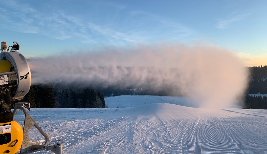 Winter sports enthusiasts enjoying a snowy day at the Orava Snow ski resort in Oravská Lesná, Žilina, Slovakia, with a view of pristine white slopes and a snowmobile.