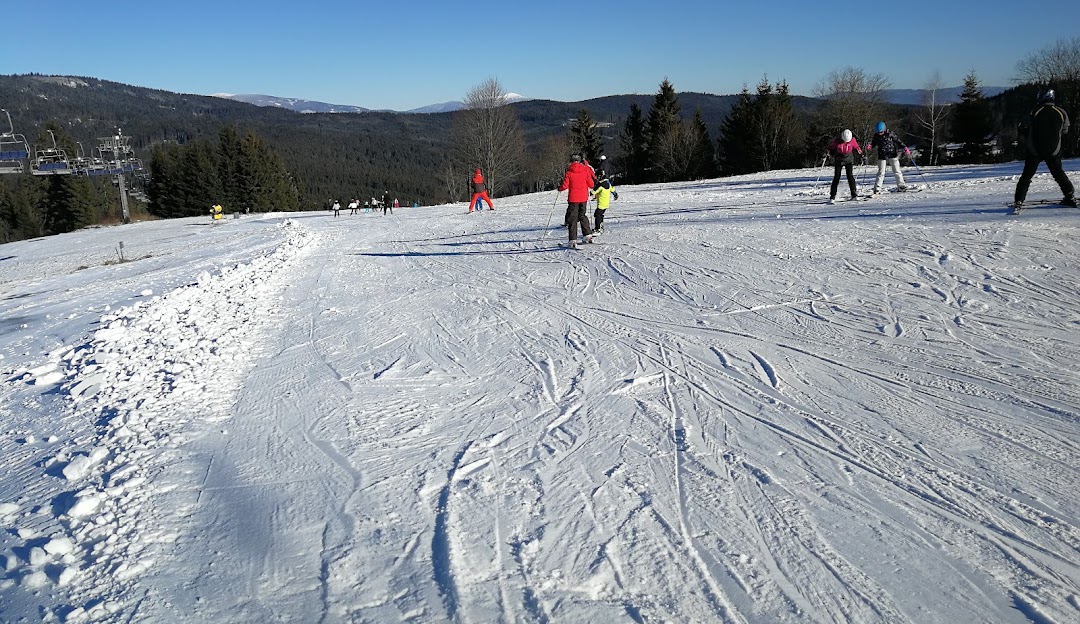Winter scene at Orava Snow in Slovakia, featuring a skier in motion amidst a bustling ski resort. A charming challet can be seen in the backdrop, adding to the scenic beauty of the winter sports centre.