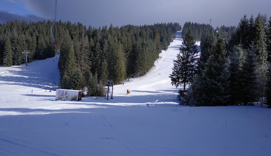 A winter sports scene at the Orava Snow resort in Slovakia, featuring skiers on snowy slopes and a cozy chalet in the background.