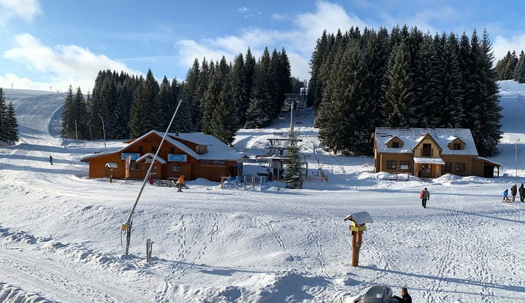 A scenic view of Orava Snow ski resort in Žilina Slovakia showcasing a cozy chalet nestled among snow-covered slopes with a ski lift in the backdrop ready for winter sports activities.