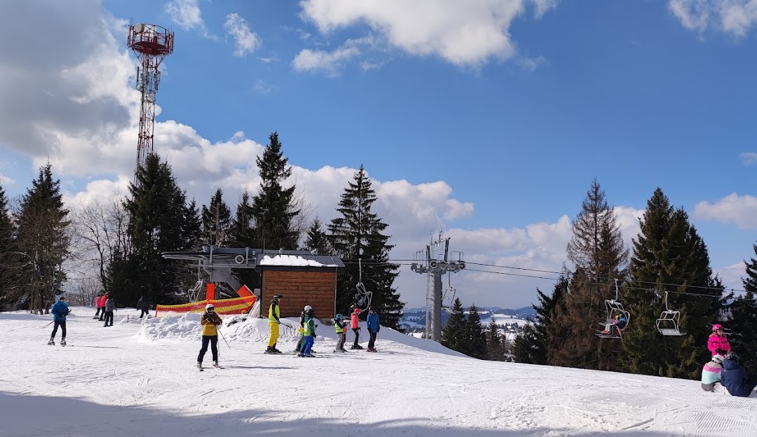 A winter scene at Orava Snow ski resort in Slovakia showcasing a vibrant winter sports scene. Visible elements include a ski lift and a distant skier navigating the slopes.
