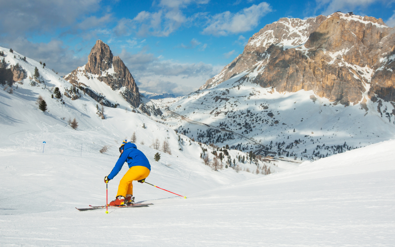 Alpe del Nevegal in Italy - a man in a blue jacket skiing down a mountain.