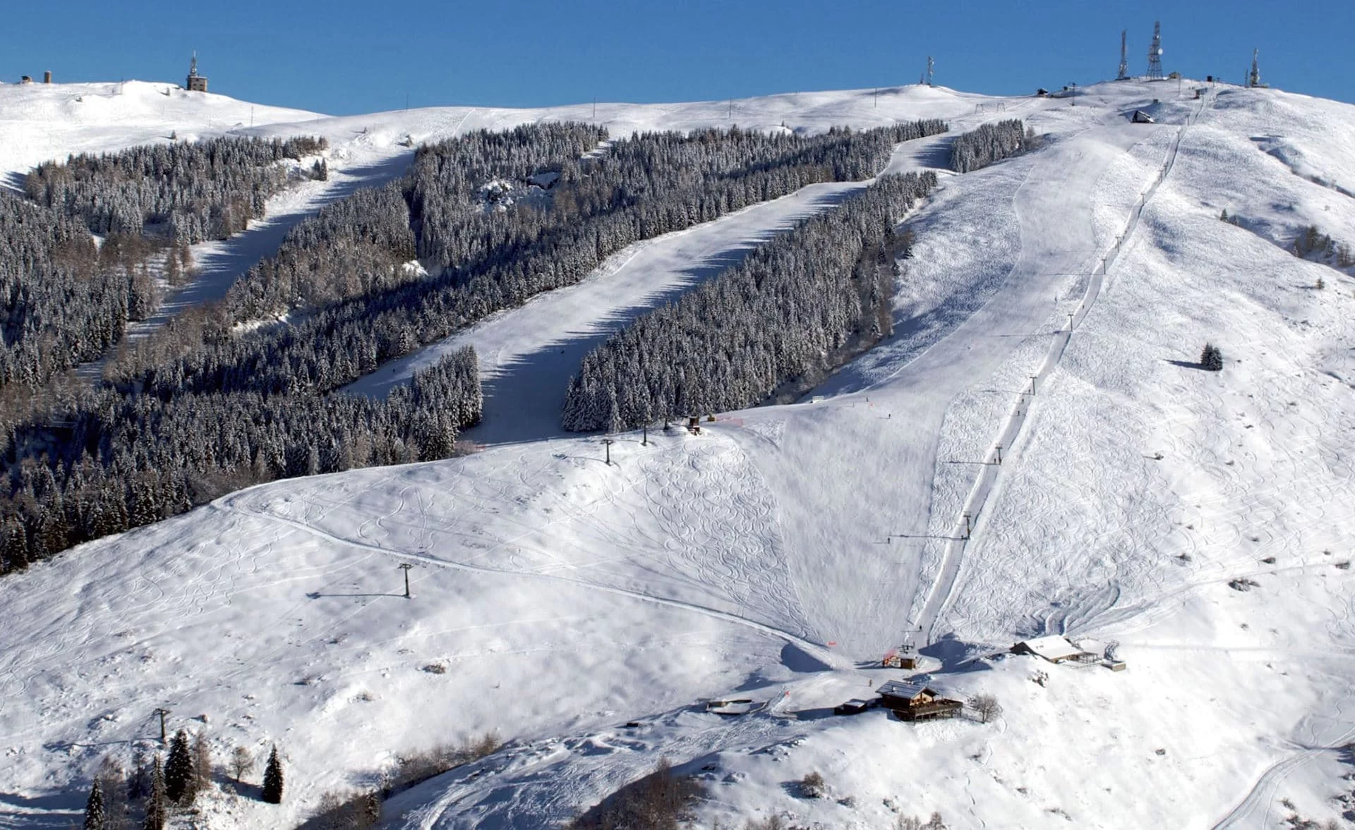 A view of Alpe del Nevegal ski resort in Italy with snow-covered slopes a ski lift and a chalet. The scene exemplifies typical winter sports activities.
