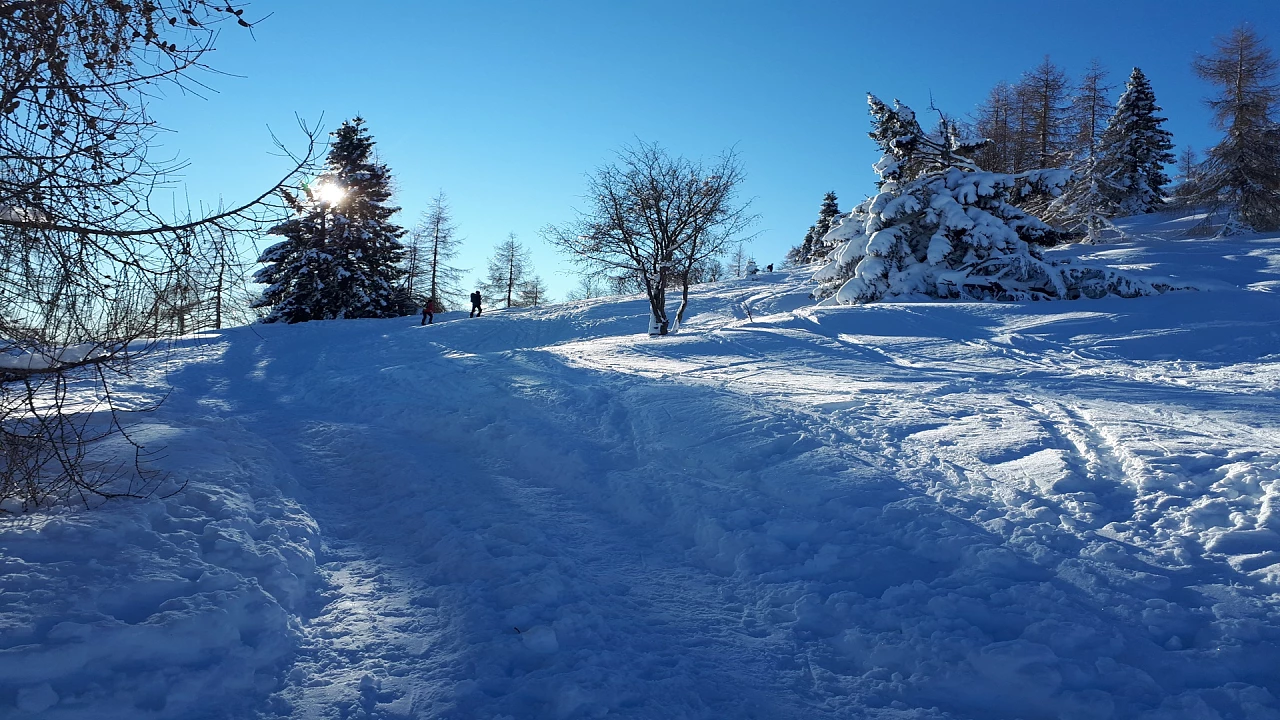 Winter scene at Alpe del Nevegal, Italy. A bustling winter sports scene unfolds with a charming chalet in the background, surrounded by a beautiful wintry landscape.