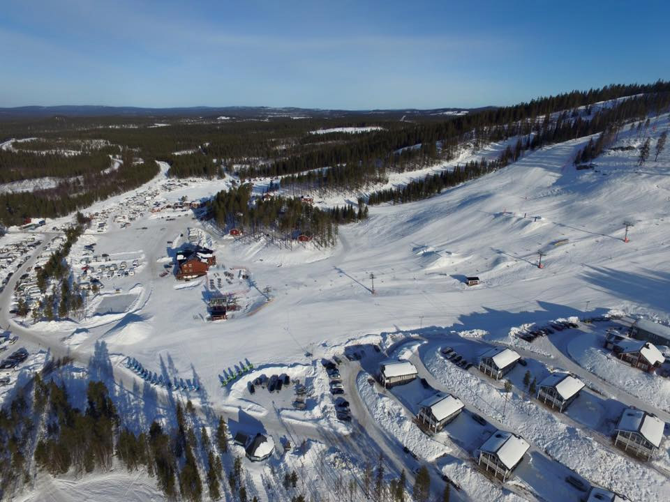 A scenic view of Kåbdalis ski resort in Northern Sweden featuring snowy slopes a ski lift and people enjoying winter sports.