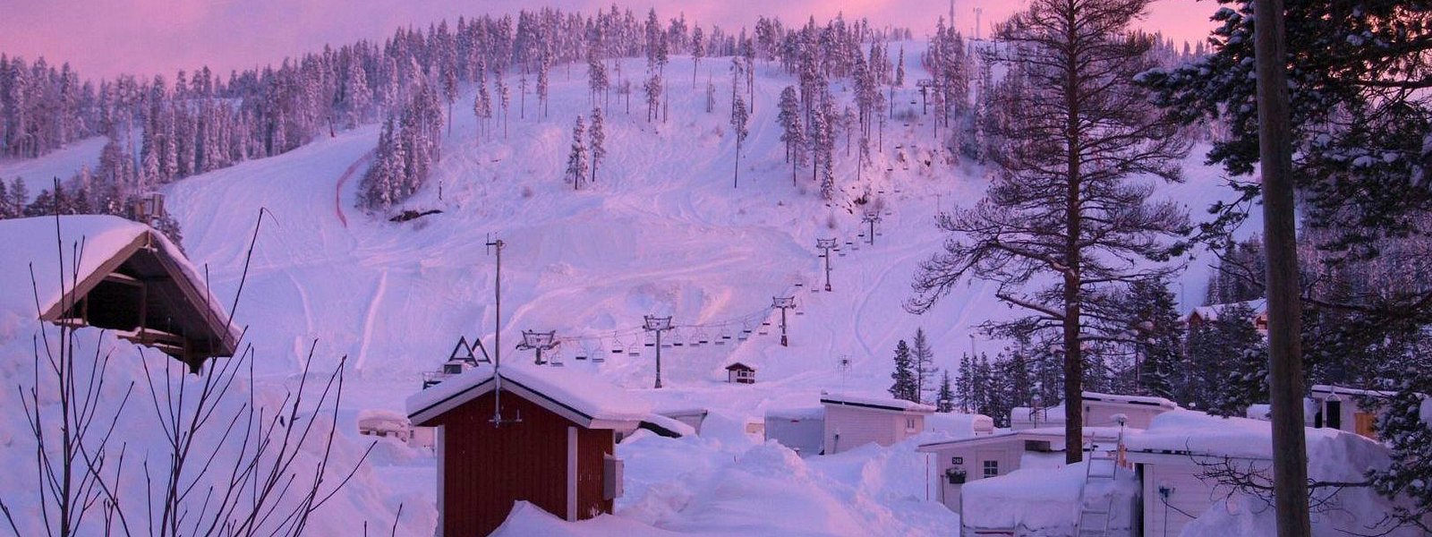 Stunning winter scene in Kåbdalis, Northern Sweden, highlighting a bustling ski resort amidst a serene winter landscape that teems with live winter sports action.