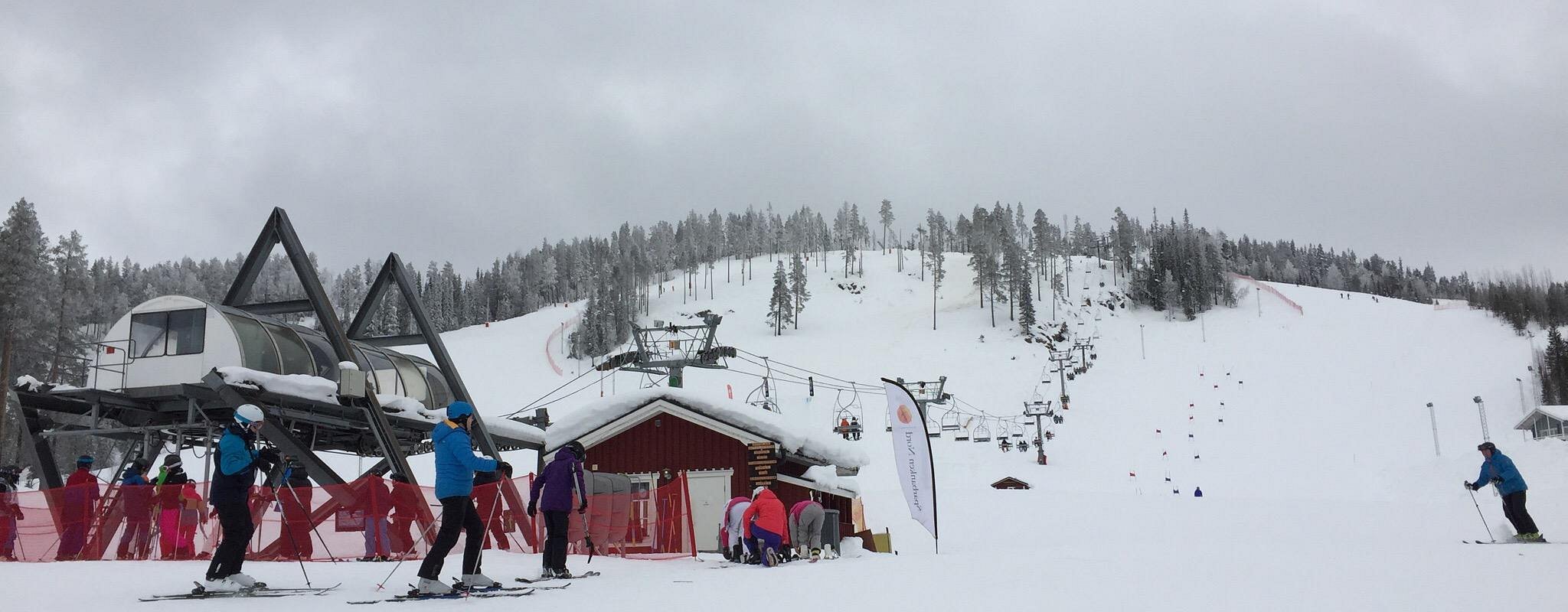 A winter scene at Kåbdalis ski resort in Norrbotten, Northern Sweden features a bustling ski lift and a skier on the snow-covered slopes, encapsulating the vibrancy of winter sports.