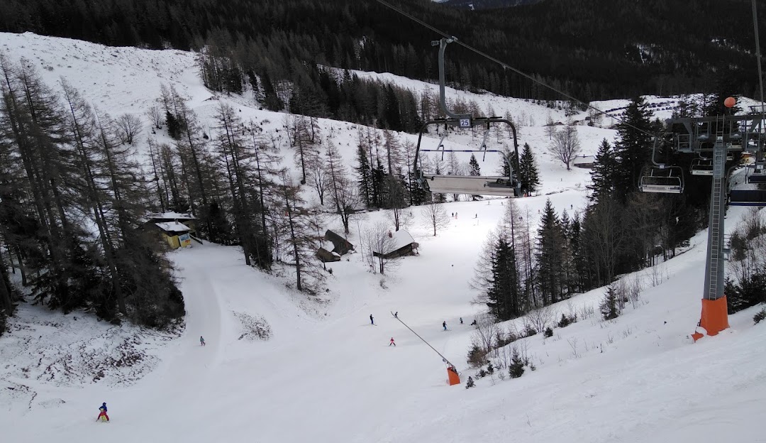 A panoramic view of Brunnalm - Hohe Veitsch ski resort in Styria Austria. Skiers enjoy the pristine slopes serviced by a ski lift under a clear sky.