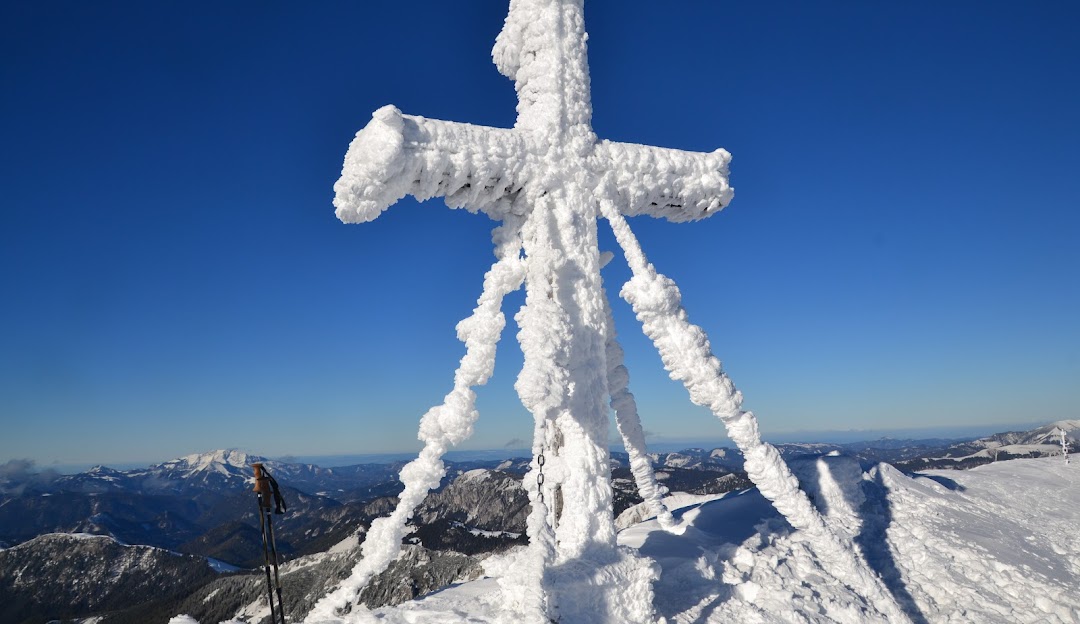A skier navigating a picturesque slope at Brunnalm - Hohe Veitsch in Styria, Austria. A chalet and peaks characterise the background in this classic winter resort scene.
