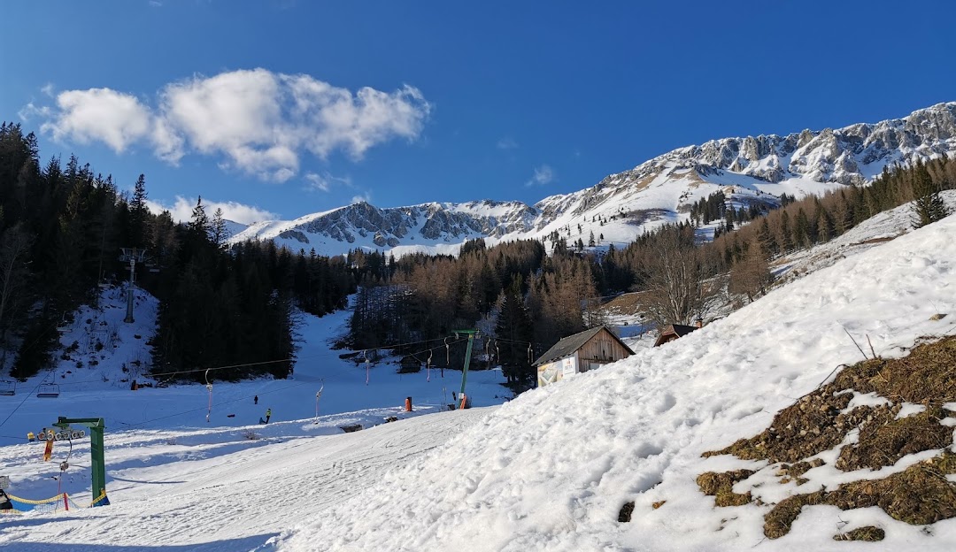 Image of a charming chalet in the picturesque winter landscape of Brunnalm - Hohe Veitsch ski resort in Hochsteiermark, Austria. Skiers and snowboarders enjoying winter sports activities.