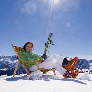 A skier and a snowboarder enjoying a winter sports scene at the serene Zauchensee | Flachauwinkl in Pongau, Salzburg, Austria. The image depicts a bustling ski resort with a charming challet nestled in the snowy landscape.