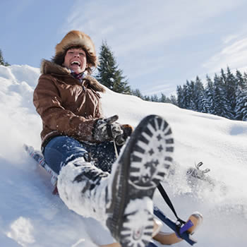 Snowboarder and skier enjoying winter sports at Zauchensee | Flachauwinkl in Pongau, Salzburg, Austria with a chalet and snowmobile nearby, all nestled in a beautiful snowy landscape.