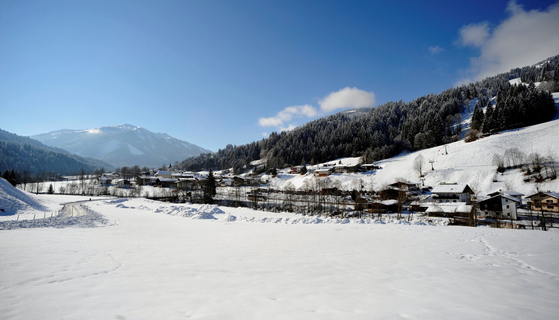 Winter sports enthusiasts enjoying activities at a sports centre in Kelchsau, Tyrol, Austria with a quaint challet sitting amidst spellbinding winter scenery in the Kitzbüheler Alpen.