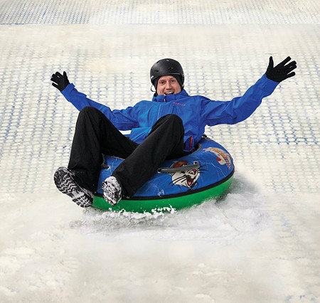 A skier and a snowboarder enjoying winter sports at The Snow Centre in Hemel Hempstead, England with a snowmobile nearby.