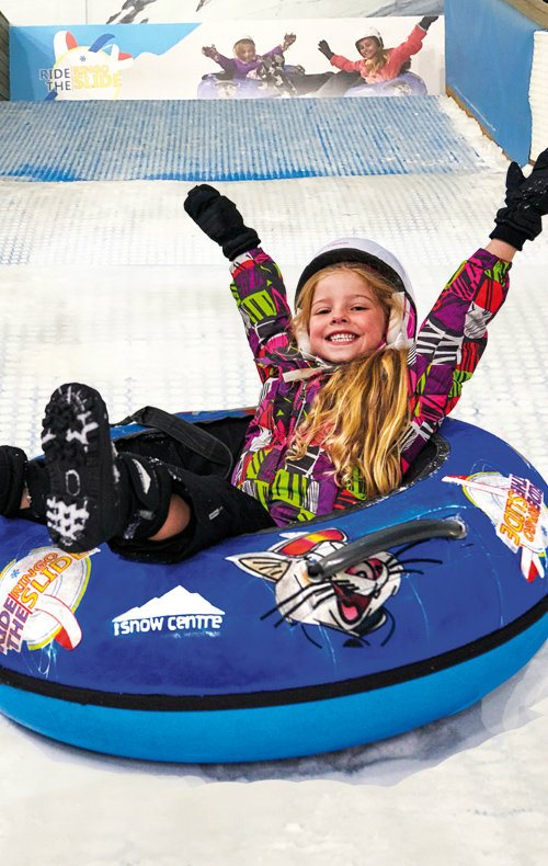 A snowboarder skillfully carving down the slopes at The Snow Centre in Hemel Hempstead, East of England, showcasing winter sports activities in indoor settings.