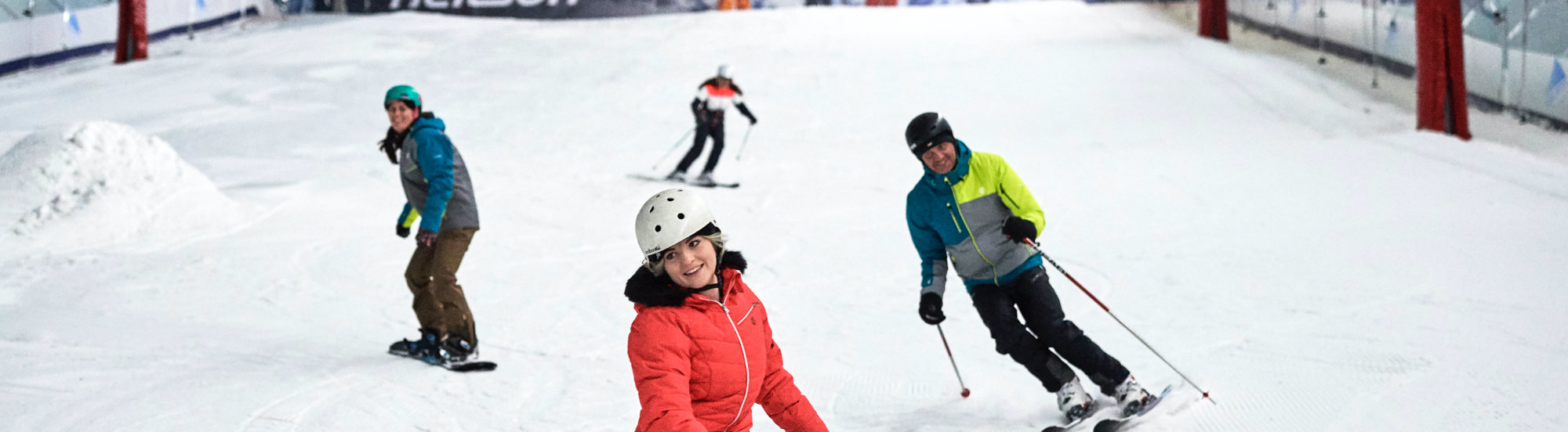 A skier enjoying a winter sports scene at The Snow Centre in Hemel Hempstead, East of England, along with a group of people and families engaged in skiing.