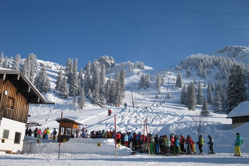 View of the snowy Wendelstein-Brannenburg ski resort in Upper Bavaria, Germany featuring ski lifts, winter sports enthusiasts, and vast snow-covered slopes.