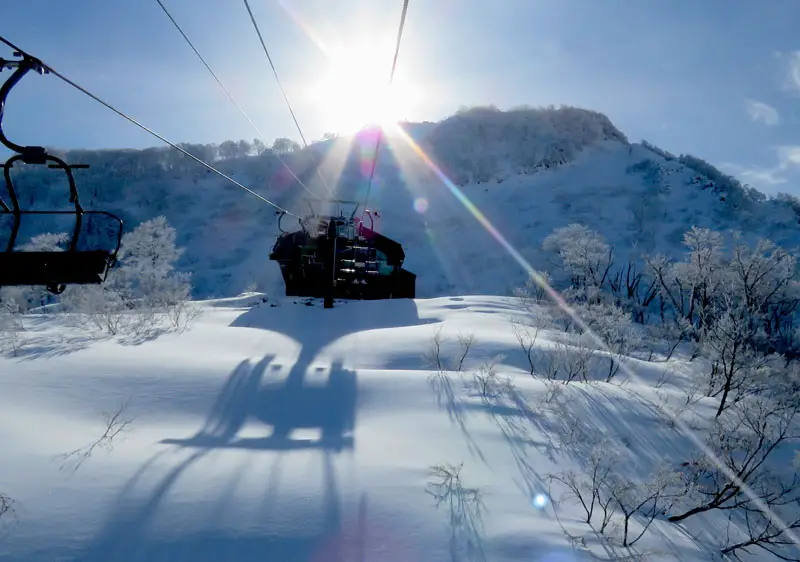 A captivating winter scenery in Kamikijima, Japan, featuring a lively winter sports scene with a snowmobile in action. Nearby, a ski lift and a skier enhance the allure of this snowy paradise.