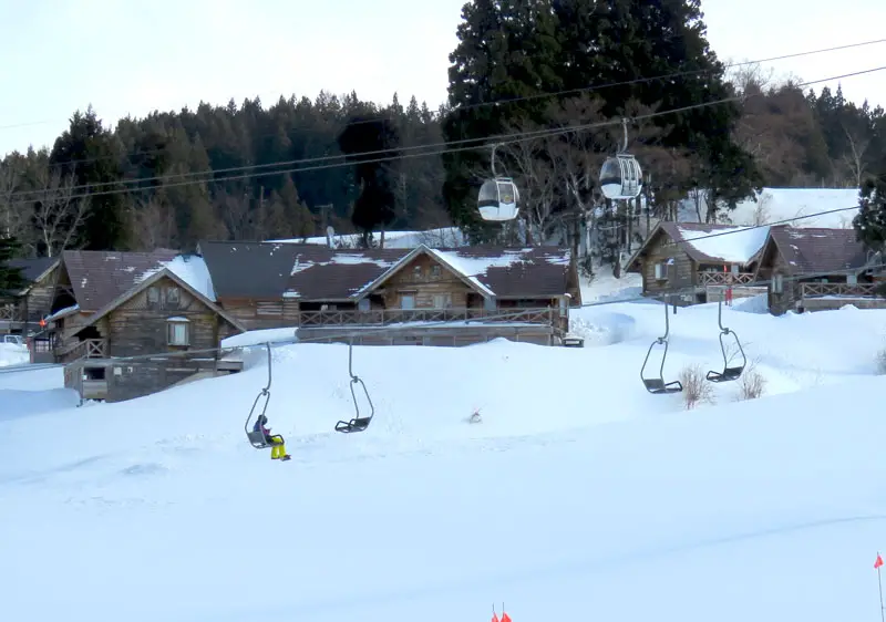 Winter sports scene at The Cupid of Romance in Chūbu, Japan. Snow blankets the ski resort, paired with a charming challet and active ski lift.