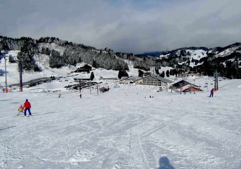 A scene from The Cupid of Romance in Nagano Japan featuring a bustling ski resort with skiers enjoying winter sports a charming chalet in the background and a ski lift nearby.