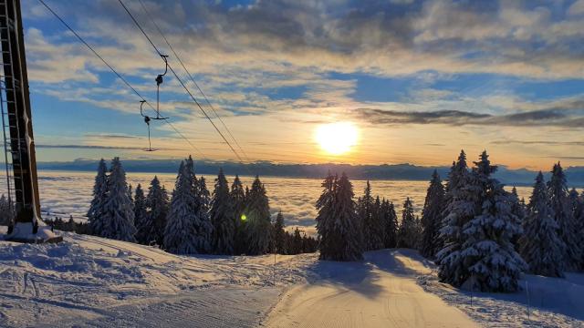 Winter sports scene at Ste-Croix - Les Rasses in Switzerland, featuring a charming chalet, a ski lift snaking up the snow-covered mountain, and majestic winter scenery at a ski resort.