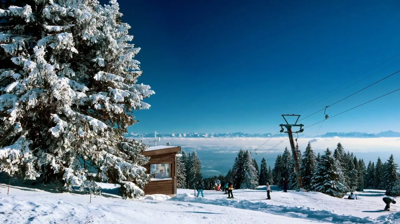 View of Ste-Croix - Les Rasses ski resort in Switzerland, featuring a ski lift amidst a winter sports scene with pristine snow-covered slopes against a stunning alpine backdrop.