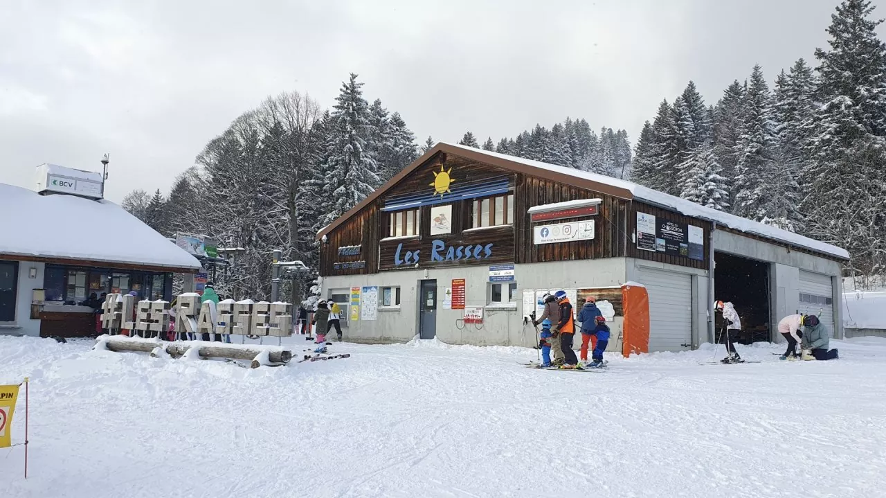 Winter view of Ste-Croix - Les Rasses in Switzerland, featuring a bustling winter sports centre amidst a serene ski resort, dotted with the occasional chalet.