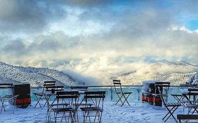 Winter scene at Superski Roata Cavnic in Romania showcasing the picturesque ski resort surrounded by snow-capped trees, with skiers enjoying the slopes.
