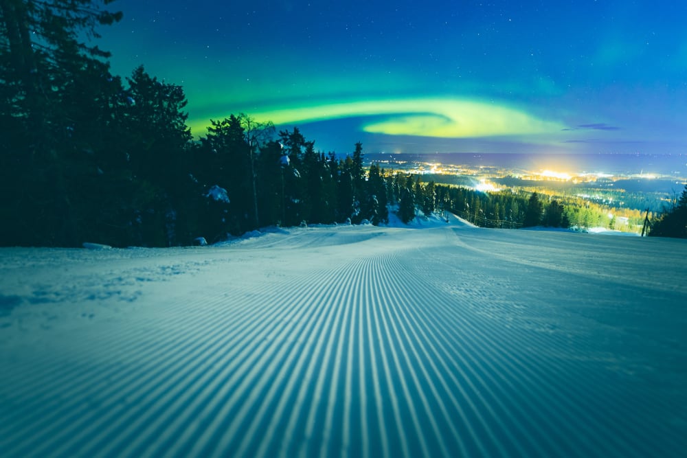 A skier enjoying the slopes at Vuokatti ski resort in Finland with a ski lift in the backdrop of the picturesque winter landscape.