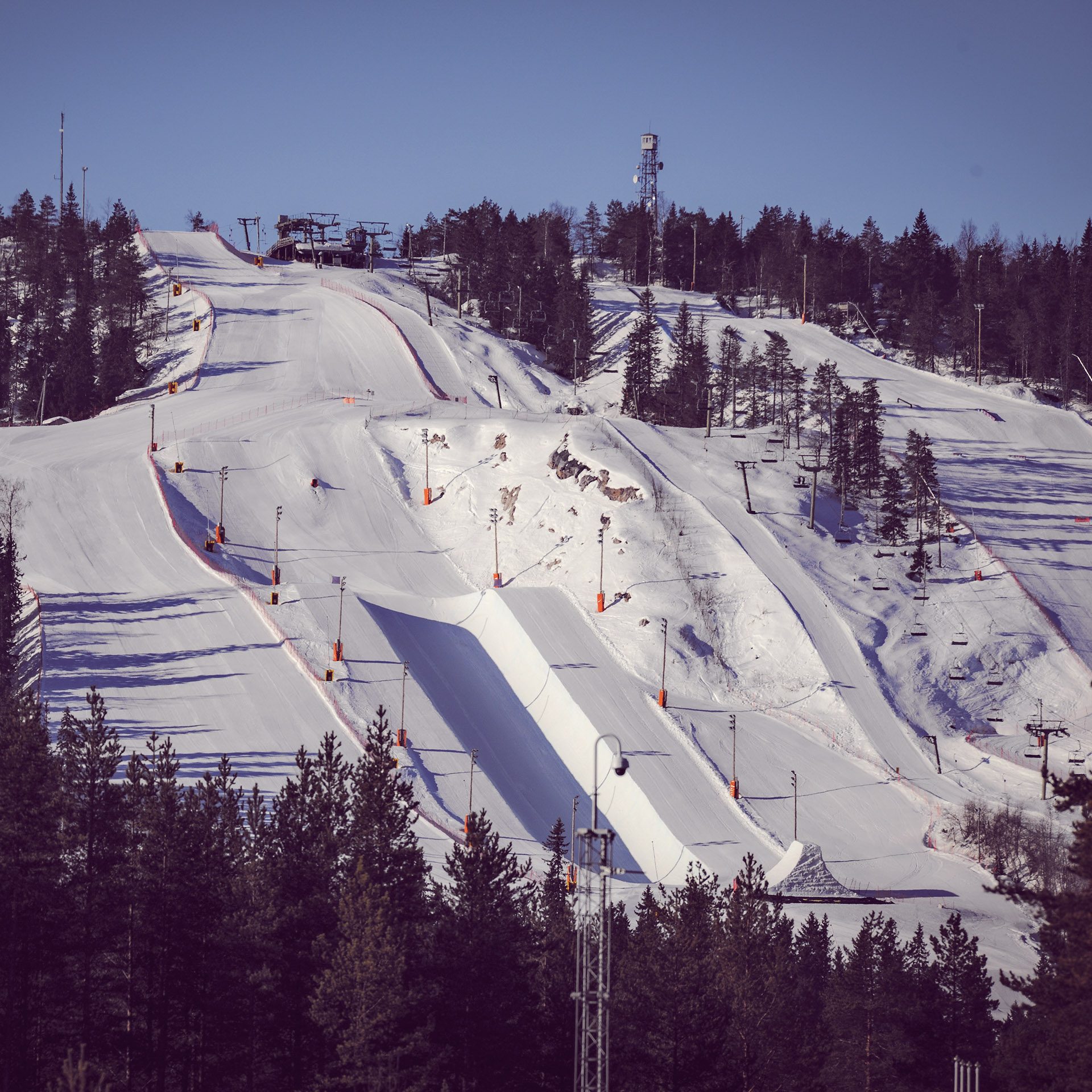 A winter sports scene at Vuokatti Ski Resort in Kainuu, Sotkamo, East Finland, with a skier gliding down the snow-covered slopes.