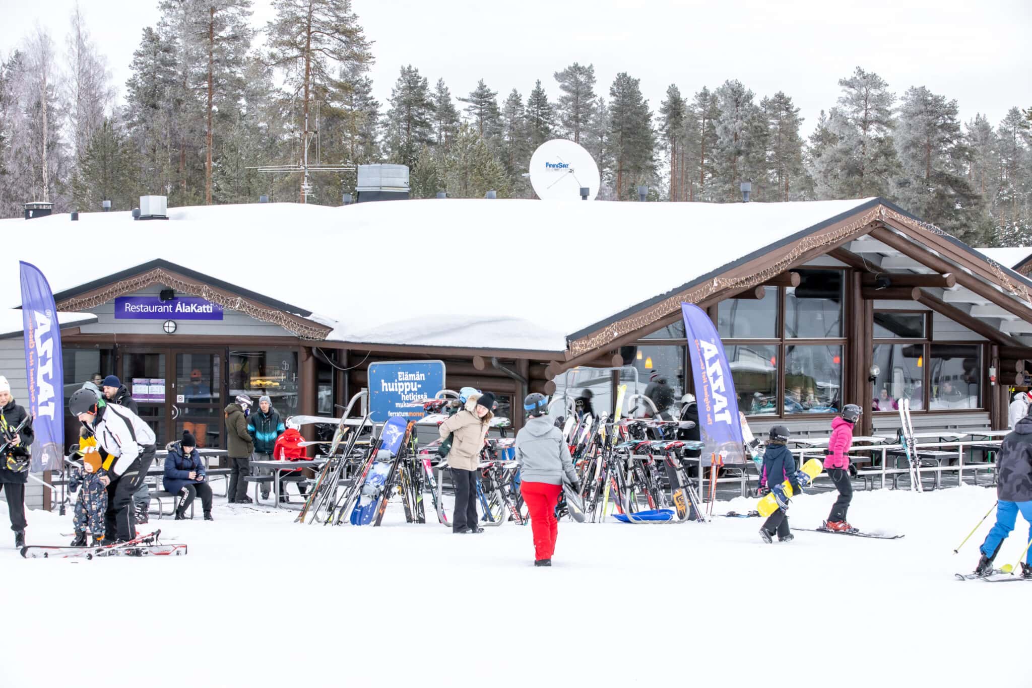 Winter sports scene at Vuokatti in Kainuu, East Finland, featuring a bustling ski resort, a ski lift, and a family enjoying skiing.