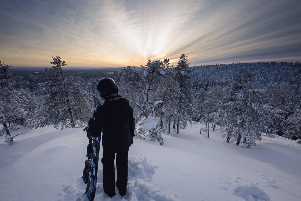 A winter sports scene in Vuokatti, Kainuu, East Finland, showcasing a picturesque snowy landscape with a skier and a snowboarder enjoying the terrain.
