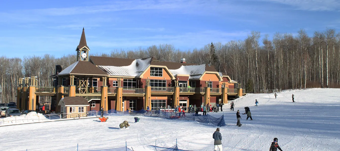 View of Kinosoo Ridge ski resort in Cold Lake, Alberta, Canada featuring bustling winter sports scene, ski lift, and a lodge amidst the white snow-covered landscape.