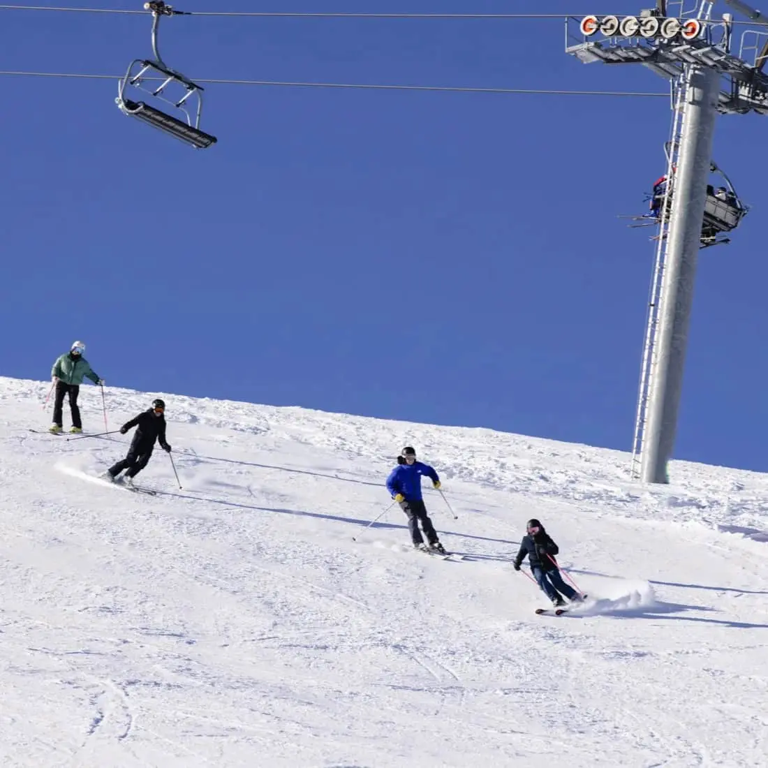 Winter scene at Mottarone ski resort in Italy, featuring skiers enjoying the slopes, a ski lift in operation, and a picturesque chalet nestled amongst the snow.