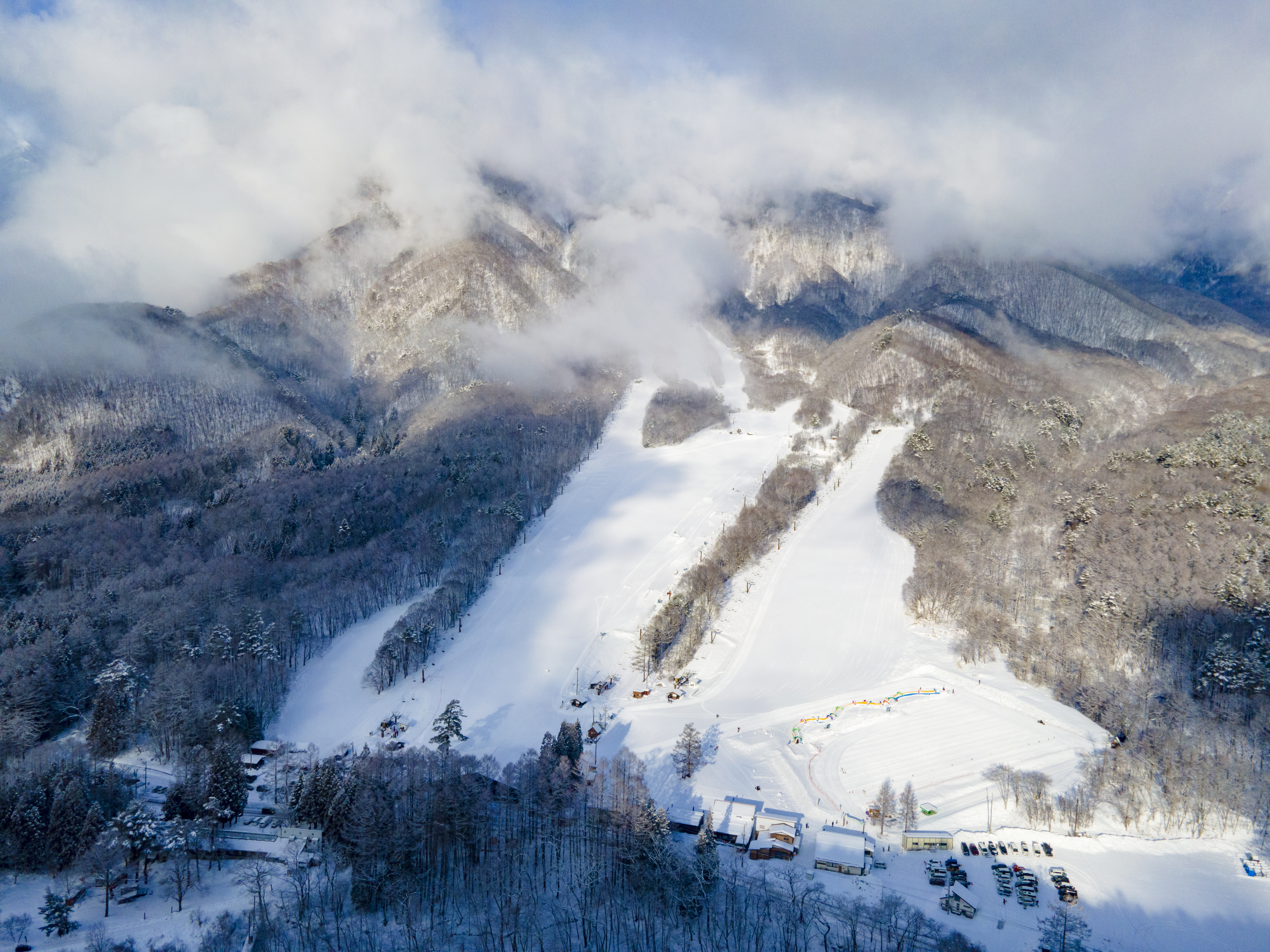 Winter scene at Jiigatake ski resort in Nagano, Japan, featuring snow-covered slopes, a mountain, and skiers enjoying the stunning winter scenery.