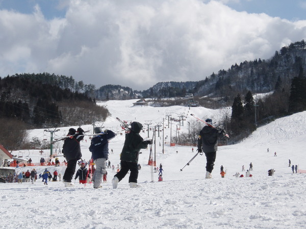 Winter scene at Mikawa Onsen ski resort in Niigata, Japan with a skier in action. A chalet and the winter sports centre add to the snowy landscape.