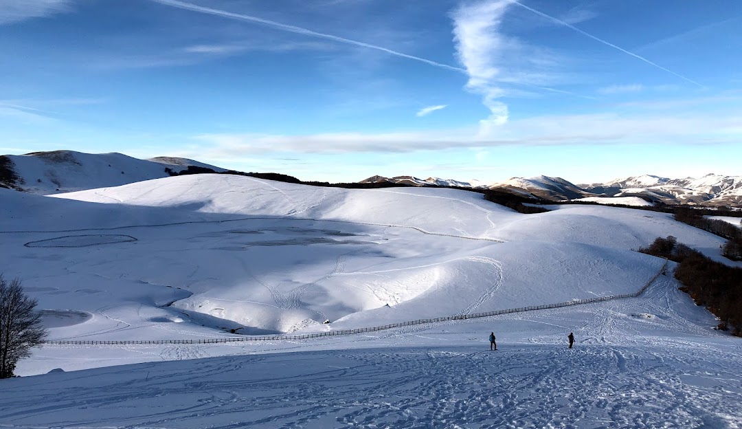 Winter sports enthusiasts enjoying a stunning winter scenery at Forca Canapine in Arquata del Tronto, Ascoli Piceno, Italy. Snow-covered mountains and a charming chalet add to the picturesque ski resort view.