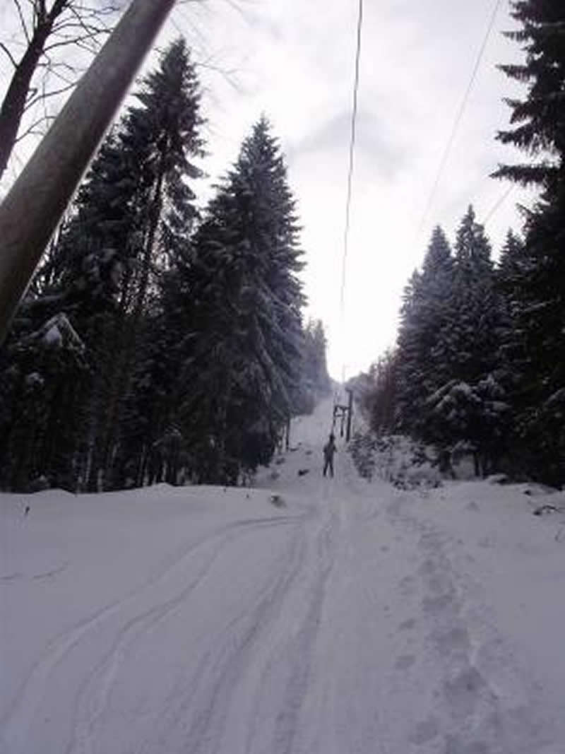 A cozy chalet nestled amidst snowy winter scenery in Igrišta Vlasenica Republika pska Bosnia and Herzegovina featuring a ski lift and winter sports enthusiasts enjoying the day.