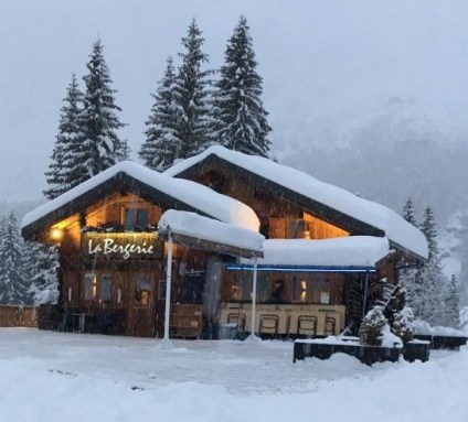 View of Passy Plaine-Joux ski resort in France, featuring a cozy lodge amidst a stunning winter landscape bustling with winter sports activities.