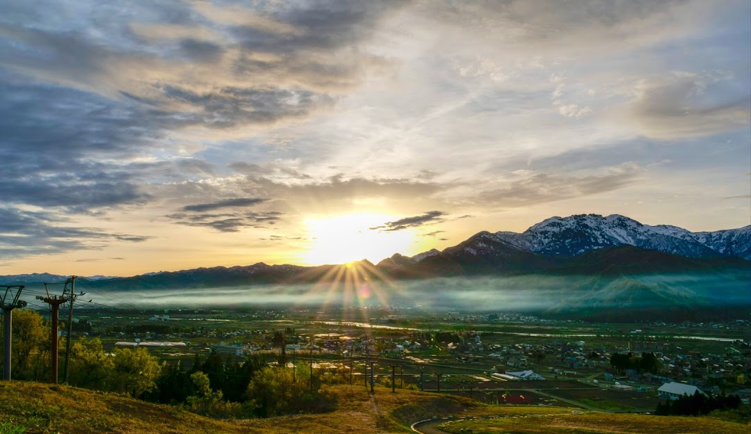 Sunny winter day at Itsukamachi in Japan, with a visible mountain and a charming chalet. The scene portrays a ski resort, suggesting a possible winter sports activity.