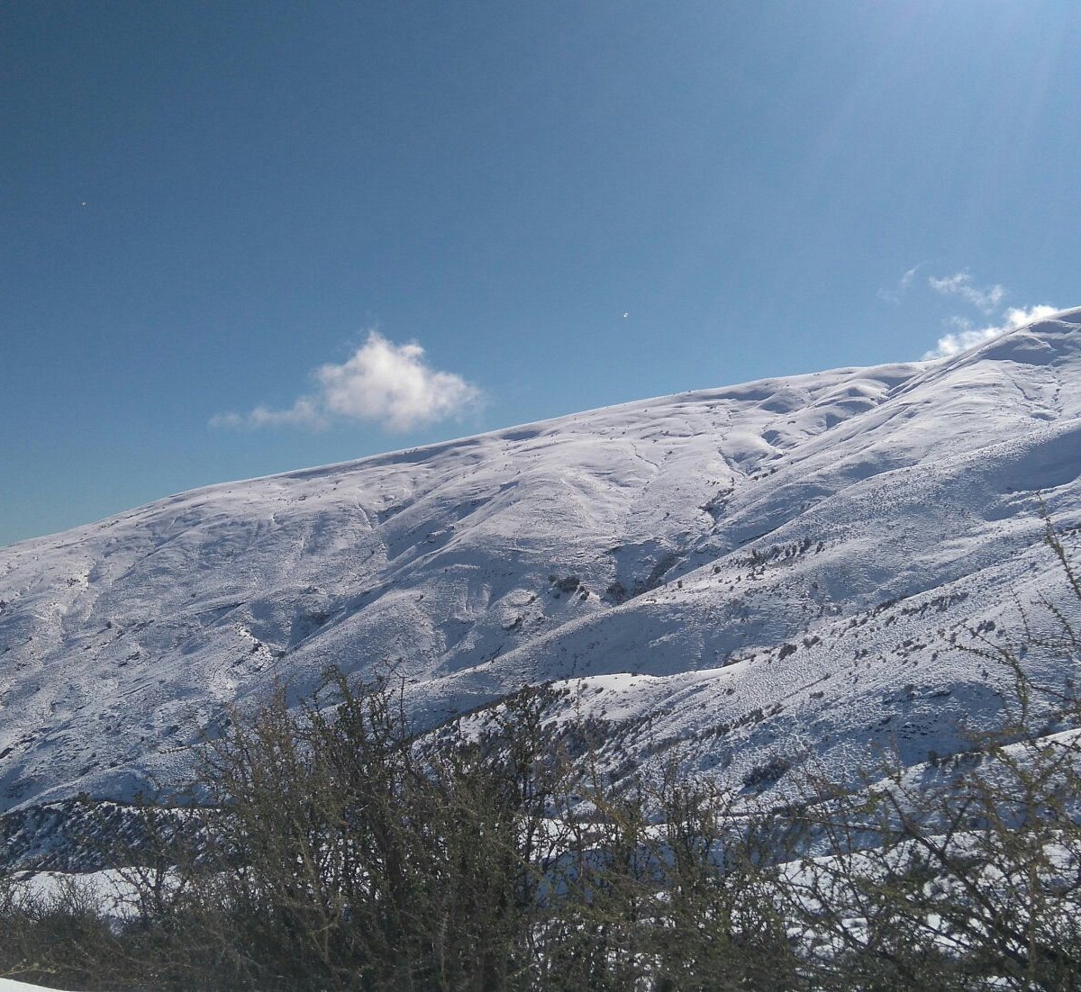 Lagunillas del Cajón del Maipo in Chile - a man riding a snowboard down a snow covered slope.