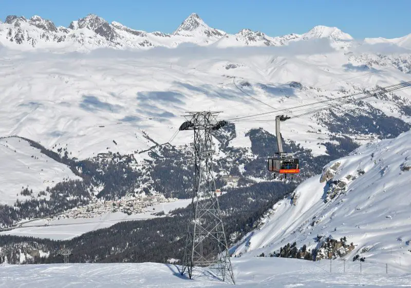 Ski resort in Corvatsch | Furtschellas, Graubünden, Switzerland featuring a charming chalet, active ski lift, and a skier enjoying the winter sports scene.