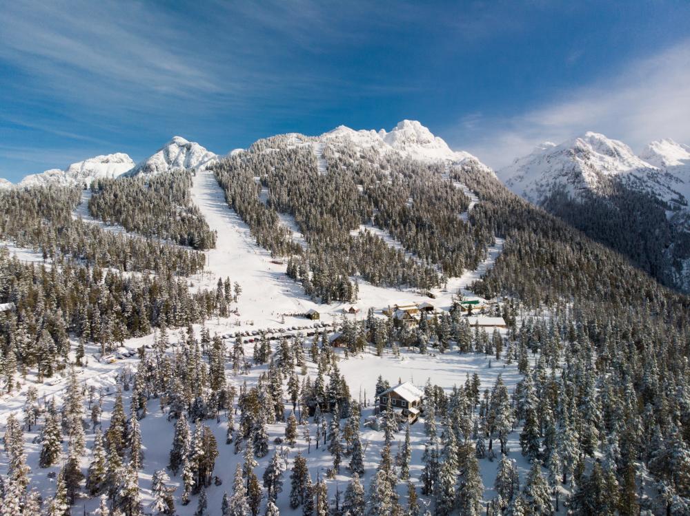 A scenic view of Mount Cain Alpine Park in Canada featuring a bustling ski resort ski lift snow-covered slopes and the daunting mountain backdrop embodying the thrill of winter sports.