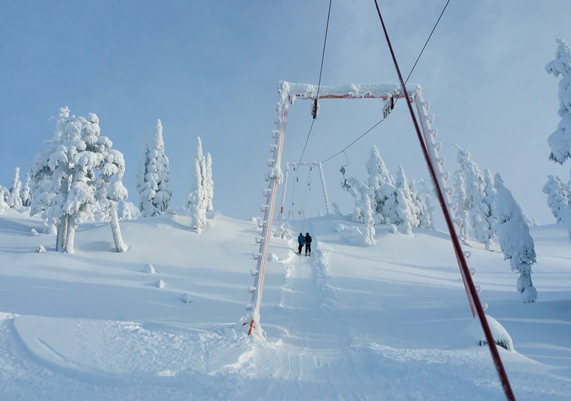 A skier enjoying a winter sports scene at Mount Cain Alpine Park in Canada, with a ski lift and the ski resort in the background.