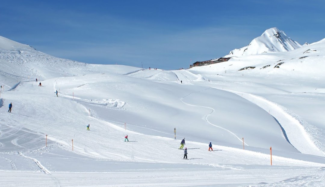 A lively winter sports scene at the SlowMountain Schatzalp-Strela in Eastern Switzerland. The image features a ski resort with a charming challet, a busy winter sports centre and vast snow-covered slopes.