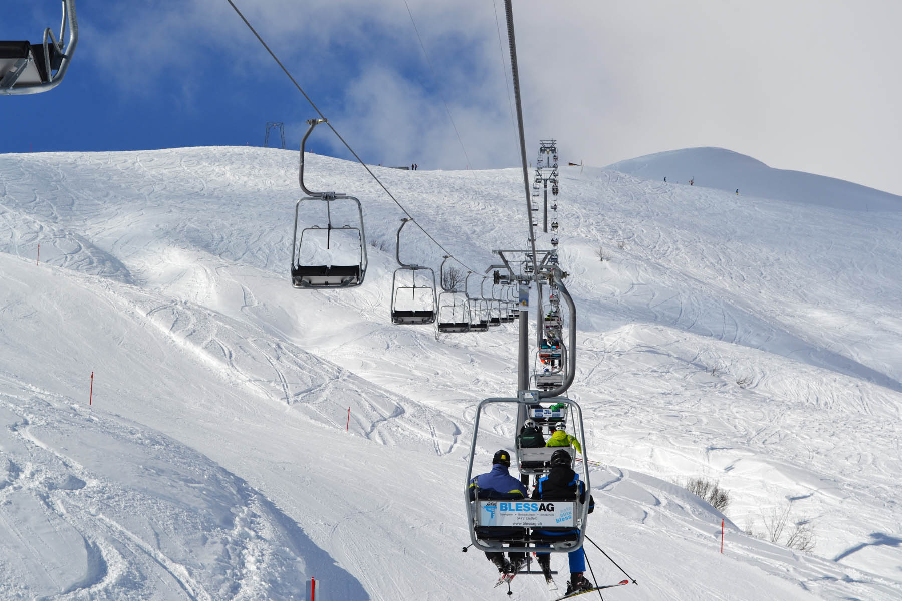 A Swiss winter scene in Bürglen; a ski lift cuts through the snowy landscape with a skier in action a chalet in the background suggests a nearby ski resort.