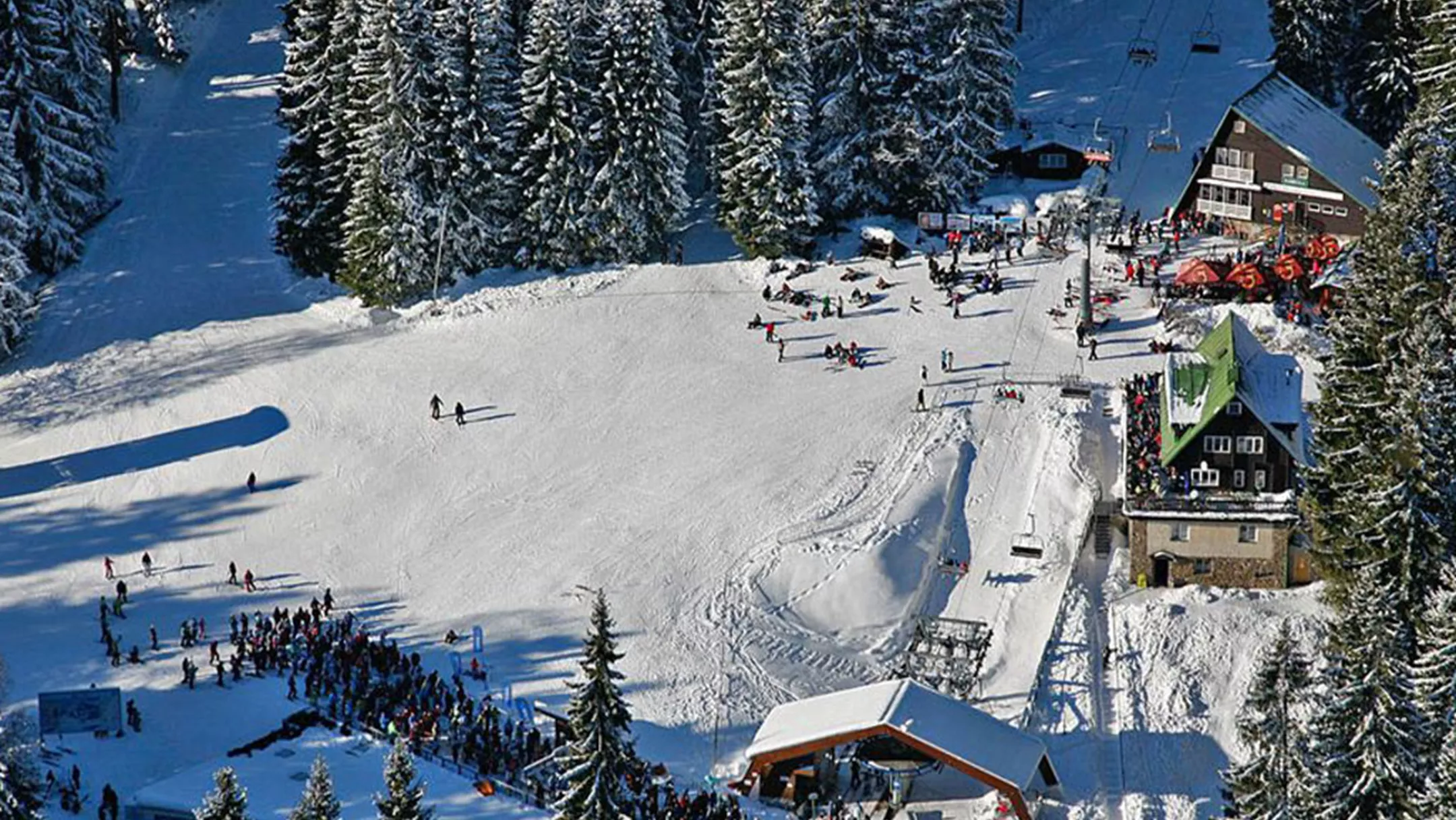 View of Špičák ski resort in the Czech Republic featuring a ski lift and chalet set against a winter sports scene.