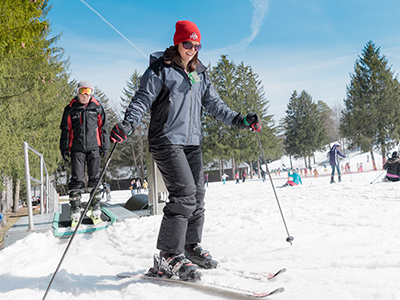 A skier and snowboarder enjoying a winter day at Snow Trails in Mansfield, Ohio, amidst other winter sports enthusiasts.