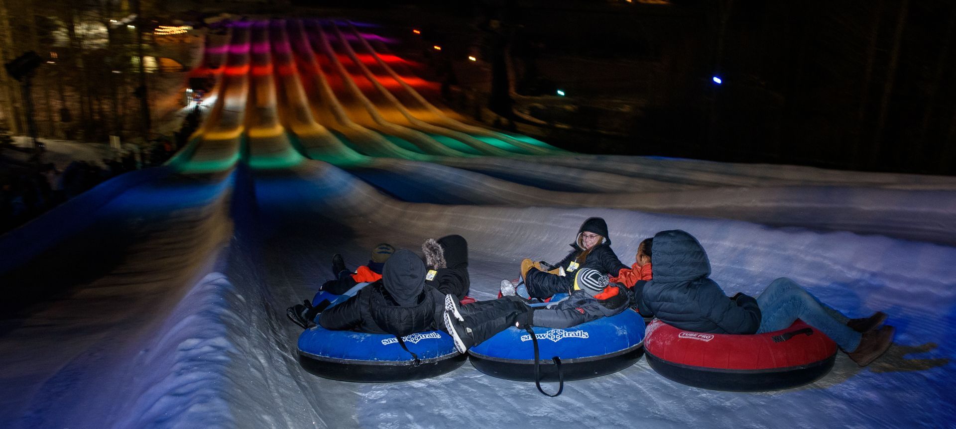 Snow Trails in USA - two people sled down a hill at night.
